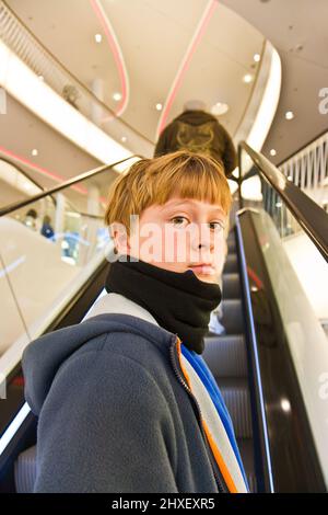 child on moving staircase looks self confident and smiles Stock Photo