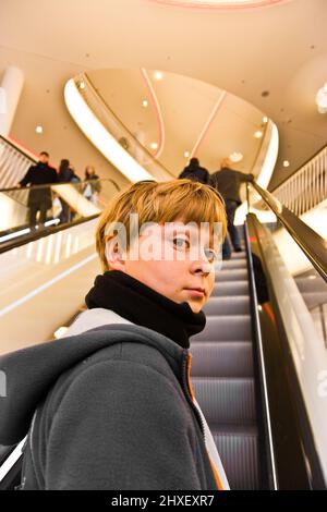 child on moving staircase looks self confident and smiles Stock Photo