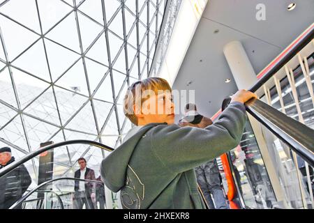 child on moving staircase looks self confident and smiles Stock Photo