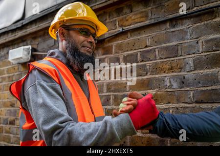 A happy, smiling Asian construction man shaking hands with a colleague. Stock Photo