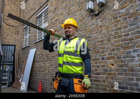 A construction working working in a building site carrying a metal bar on his shoulder. Stock Photo