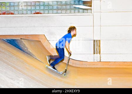 boy with scooter is going airbornein the skate hall Stock Photo