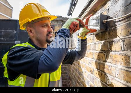 A construction worker fitting outdoor lighting. Stock Photo