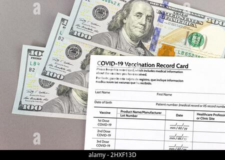 COVID-19 Vaccination Record Card, immunization certificate for travel on one hundred American dollars bills. 100. Buying fake certificates Stock Photo