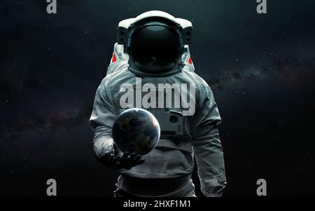 Astronaut holding Earth planet in hand. 3D sci-fi art. Elements of image provided by Nasa Stock Photo
