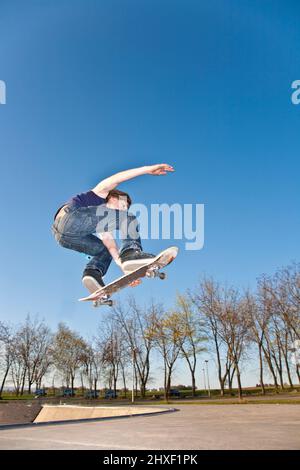 boy with skate bard is going airborne at a skate park Stock Photo