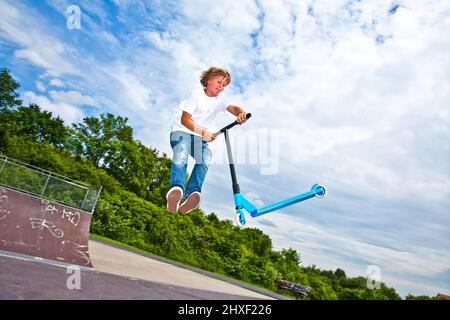 young boy with scooter is going airborne Stock Photo