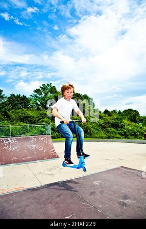 young boy with scooter is going airborne Stock Photo