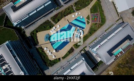 A sunny bird's-eye view. Clip. View of the resort area with a swimming pool, slides, sun umbrellas, hotels and a road for tourists Stock Photo