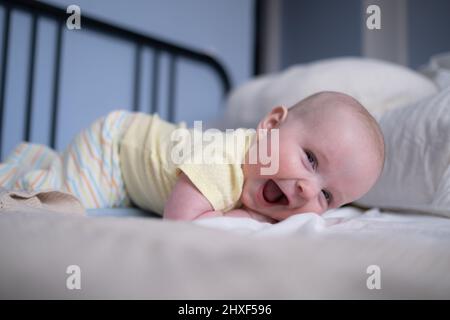Cute happy 6 month baby girl in diaper lying and playing Stock Photo