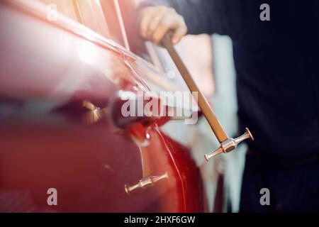 Car body repair, removal of dents paintless with knock tool. Stock Photo