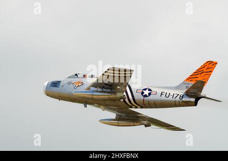 North American F-86A Sabre vintage jet plane. United States Air Force 1950s classic fighter jet in tiger scheme flying at an airshow. G-SABR Stock Photo