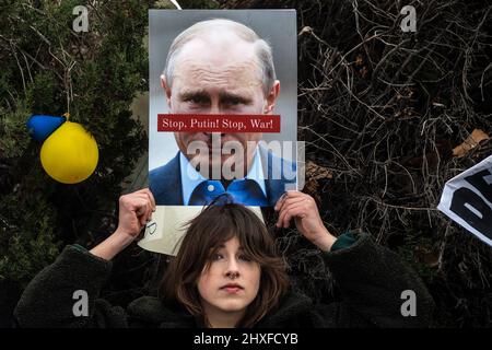 Madrid, Spain. 12th Mar, 2022. A young woman is seen carrying a placard with the picture of Russian President Vladimir Putin during a protest against war. Ukrainians and Russians living in Madrid gathered to protest in front of the Russian embassy against the Russian invasion of Ukraine demanding the end of war. Credit: Marcos del Mazo/Alamy Live News Stock Photo