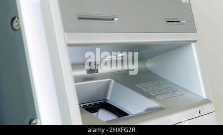 ATM bank machine and male hand performing financial transactions. HDR. Close up of man putting money inside a bank machine. Stock Photo