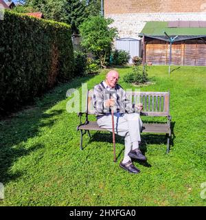 Old man enjoys sitting on a bench Stock Photo - Alamy