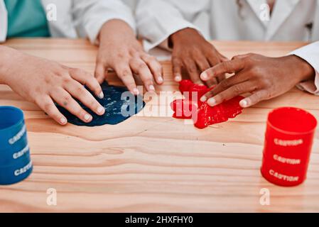 Were getting stuck in the fun of it all. Cropped shot of two unrecognizable school pupils playing and experimenting with slime in science class at Stock Photo