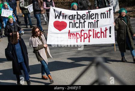 Crailsheim, Germany. 12th Mar, 2022. 'We work with heart, not compulsory vaccination!' reads a placard displayed by people at a demonstration against the federal government's Corona measures. Credit: Christoph Schmidt/dpa/Alamy Live News Stock Photo