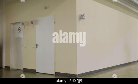 A washroom inside a shopping mall. HDR. Beige wall with white sign and silhouettes of man and woman at the public toilet. Stock Photo
