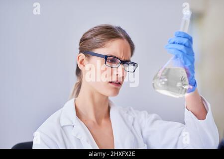 Advancing science through methodical research. Shot of a scientist examining a beaker of liquid while standing in a laboratory. Stock Photo