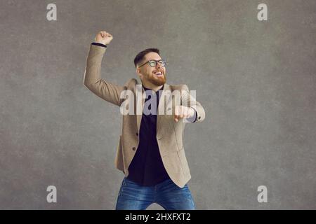 Young caucasian business man expressing riding bike over grey background Stock Photo