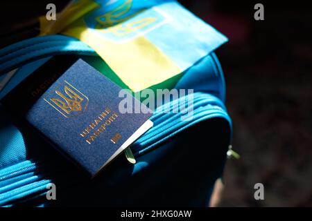 Ukrainian refugees luggage with passport and yellow-blue flag. Evacuation of civilians, families from Ukraine crossing the border. Stop war, support U Stock Photo