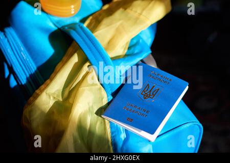 Ukrainian refugees luggage with passport and yellow-blue flag. Evacuation of civilians, families from Ukraine crossing the border. Stop war, support U Stock Photo