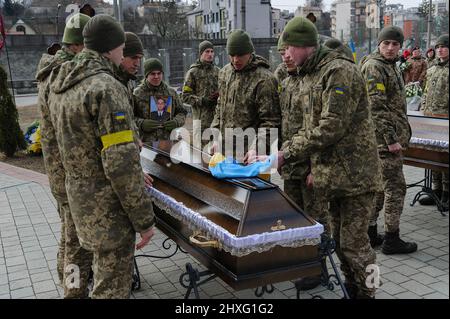 Ukrainian servicemen cover a coffin of Ukrainian soldier who was killed during the battles with Russian troops with Ukrainian flag .  A funeral ceremony was held at Saint Peter and Paul Garrison Church to pay tribute to the three soldiers: Dmitro Kotenko, Kirill Moroz and Vasil Vyshivany, who died near Kherson during the Russian aggression in Ukraine. Stock Photo