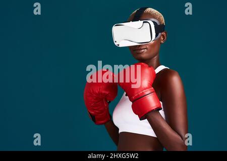 Taking training to a new level. Cropped shot of an attractive young female boxer standing alone and using a vr headset while boxing. Stock Photo