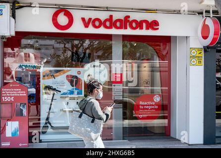 Alicante, Spain. 11th Mar, 2022. A pedestrian uses a smartphone as she walks past British multinational telecommunications corporation and phone operator, Vodafone, store in Spain. (Photo by Xavi Lopez/SOPA Images/Sipa USA) Credit: Sipa USA/Alamy Live News Stock Photo