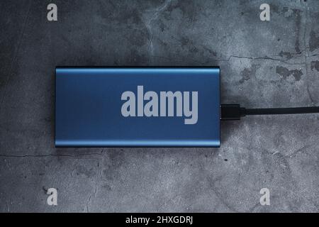 Portable External Battery Power Bank blue with USB Cord on a dark textured background for charging Gadgets Stock Photo