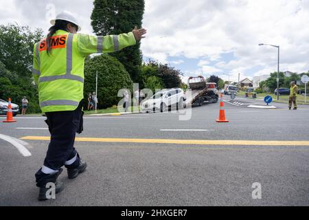 Tauranga New Zealand - December 16 2015; Man with arm out directs traffic as tow truck loads damaged car following car accident on city street. Stock Photo