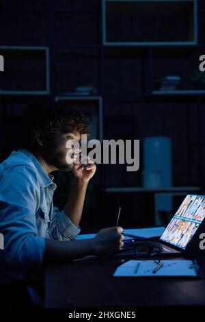 Young indian business man having video call virtual meeting late at night. Stock Photo