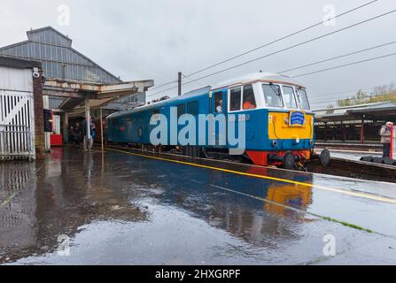 Preserved class 86 electric locomotive 86259 hauling a West Coast railways charter train st Preston railway station reflected in the wet platform
