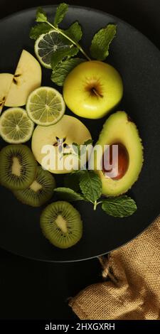 Fruit yellow border of different fruits, top view. Dramatic kitchen concept of green fruits on black background with canvas. Flat lay. Vertical border Stock Photo