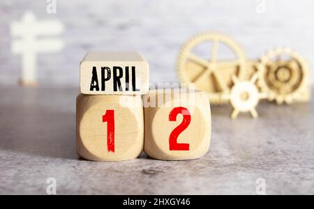 Calendar for April 12 : cubes with the numbers 0 and 12, the name of the month of April in English, a bouquet of blooming snowdrops on a yellow backgr Stock Photo