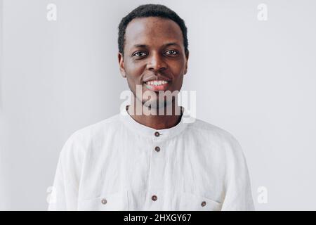 Portrait of handsome positive young African-American man in white shirt looking into camera on light grey background closeup Stock Photo