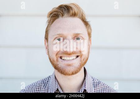 Redhead young adult man smiling while standing outdoors Stock Photo