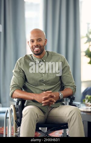 The only disability in life is a bad attitude. Cropped shot of a young man sitting in his wheelchair at home. Stock Photo