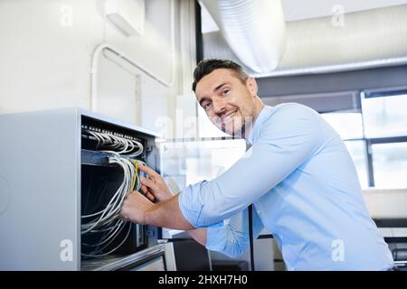Youll be online in one more minute. Portrait of a smiling computer engineer working on a server. Stock Photo