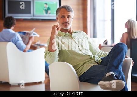 Every office needs a place to relax. Shot of a man sitting confidently on a chair indoors. Stock Photo