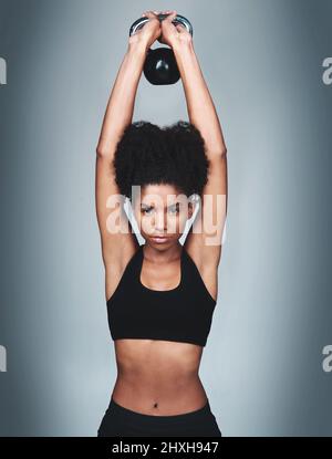 Be determined to reach your goals. Studio shot of a fit young woman posing with a kettle bell against a grey background. Stock Photo