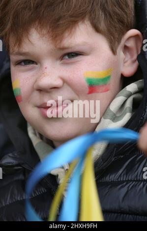 Peterborough, UK. 12th Mar, 2022. A child with a Lithuanian flag painted on his cheek waves Ukrainian coloured ribbons. At a time when Ukraine is under attack from Vladimir Putin's Russia Lithuanians celebrate their restoration Independence Day at Peterborough Cathedral. They stand in support of Ukraine and hold the Ukrainian flags and ribbons. Lithuania regained their freedom from the Soviet Union on March 11th 1990. A short prayer and a minute's silence were held for the fallen defenders of freedom. Credit: SOPA Images Limited/Alamy Live News Stock Photo