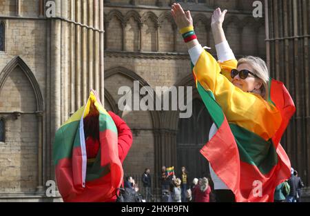 Members of the Lithuanian community wear flags like cloaks and celebrate their support for Ukraine at the end of the prayer ceremony. At a time when Ukraine is under attack from Vladimir Putin's Russia Lithuanians celebrate their restoration Independence Day at Peterborough Cathedral. They stand in support of Ukraine and hold the Ukrainian flags and ribbons. Lithuania regained their freedom from the Soviet Union on March 11th 1990. A short prayer and a minute's silence were held for the fallen defenders of freedom. (Photo by Martin Pope/SOPA Images/Sipa USA) Stock Photo