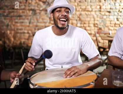 Looking relaxed. Cropped shot of a young ethnic playing drums indoors. Stock Photo