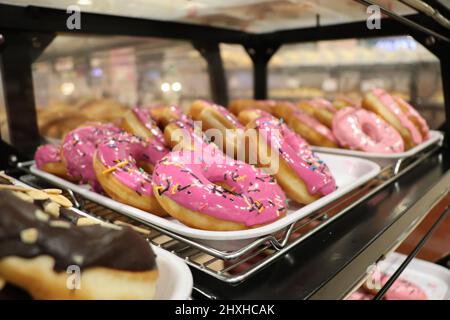 A tray full of pink donuts with sprinkles on top. Stock Photo