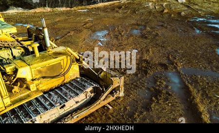 Excavators are out clearing the dirt during winter with ice and snow on the ground. Spring is around the corner as snow begins to melt soaking the gro Stock Photo