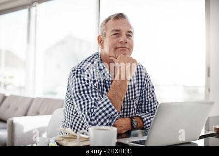 The internet keeps me connected to all I need. Portrait of a mature man working on a laptop at home. Stock Photo