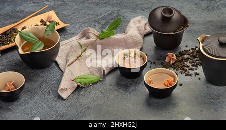 Asian tea set on dark background. Plant leaves, natural herbal tea composition. Stock Photo
