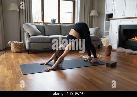 Woman standing in asana on mat in modern living room Stock Photo
