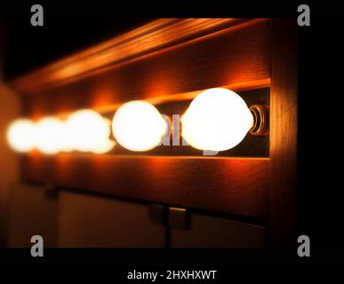 An array of 5 incandescent bulbs arranged horizontally set to lit in the dressing room. Stock Photo